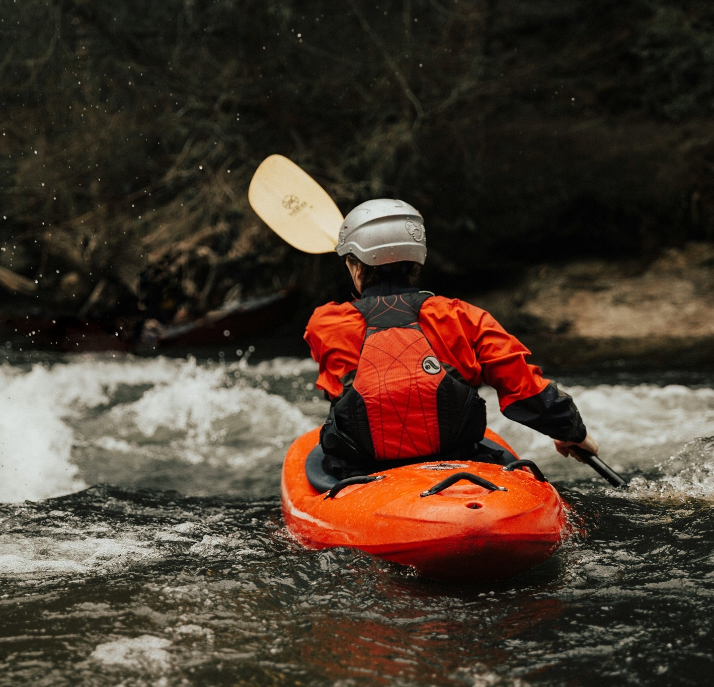 A person in a kayak paddling in a river.