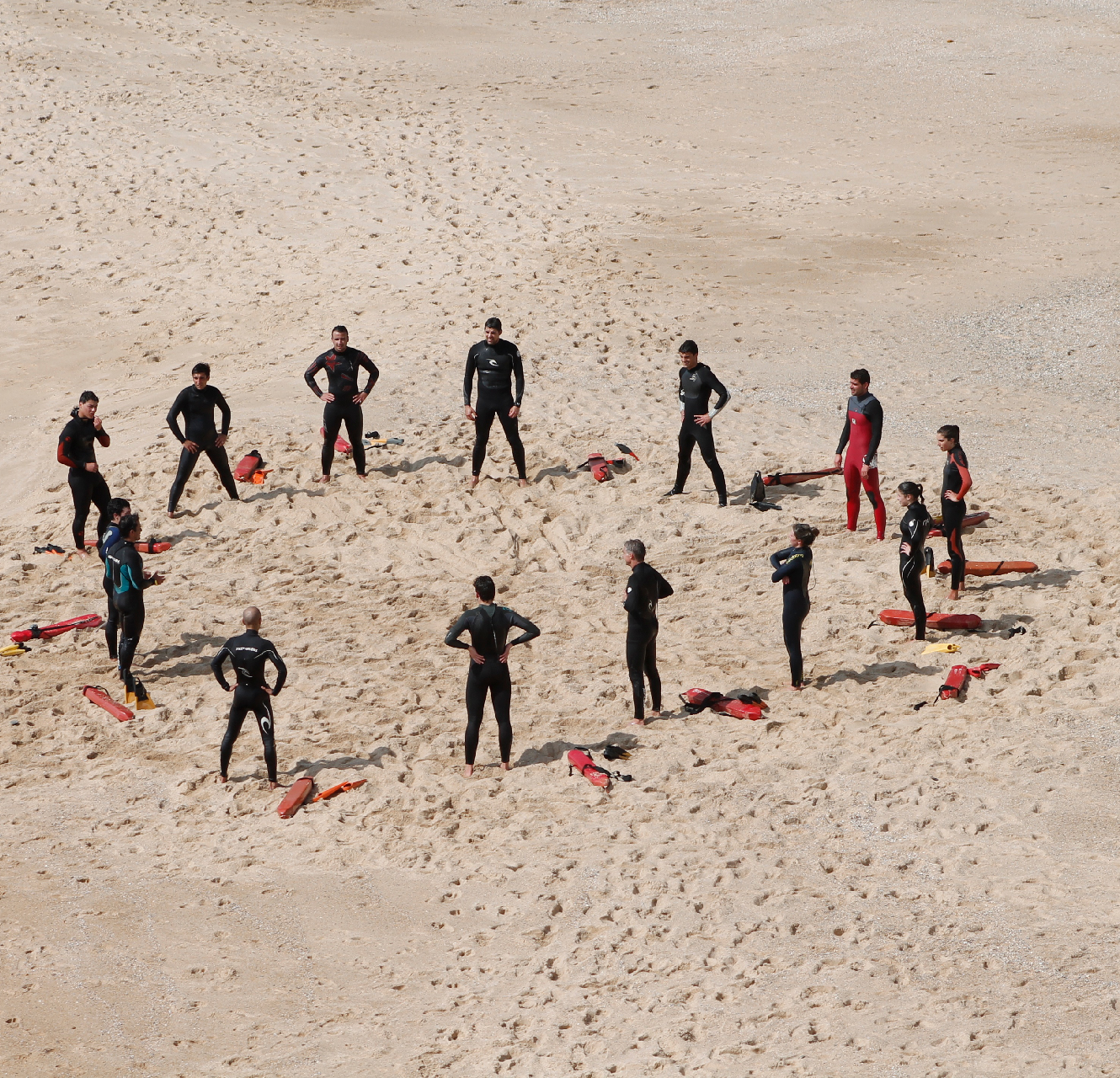 People standing in a circle on a beach.